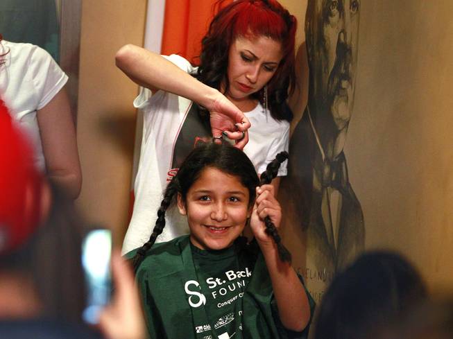 Victoria Lopez-Sosa holds up a braid during the St. Baldrick's head shaving fundraiser for cancer Saturday, March 1, 2014 at McMillan's Irish Pub. Lopez-Sosa was saving her hair to donate to Locks of Love.